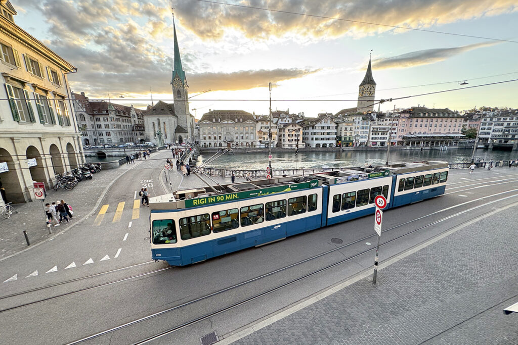 Eine Straßenbahn fährt an einem Fluss entlang.