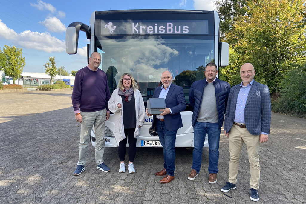 Vier Personen stehen vor einem Bus.