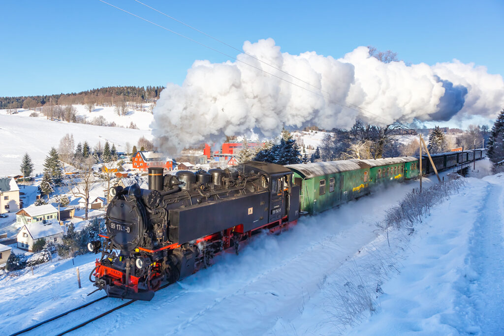 Ein Dampfzug fährt durch schneebedeckte Felder.