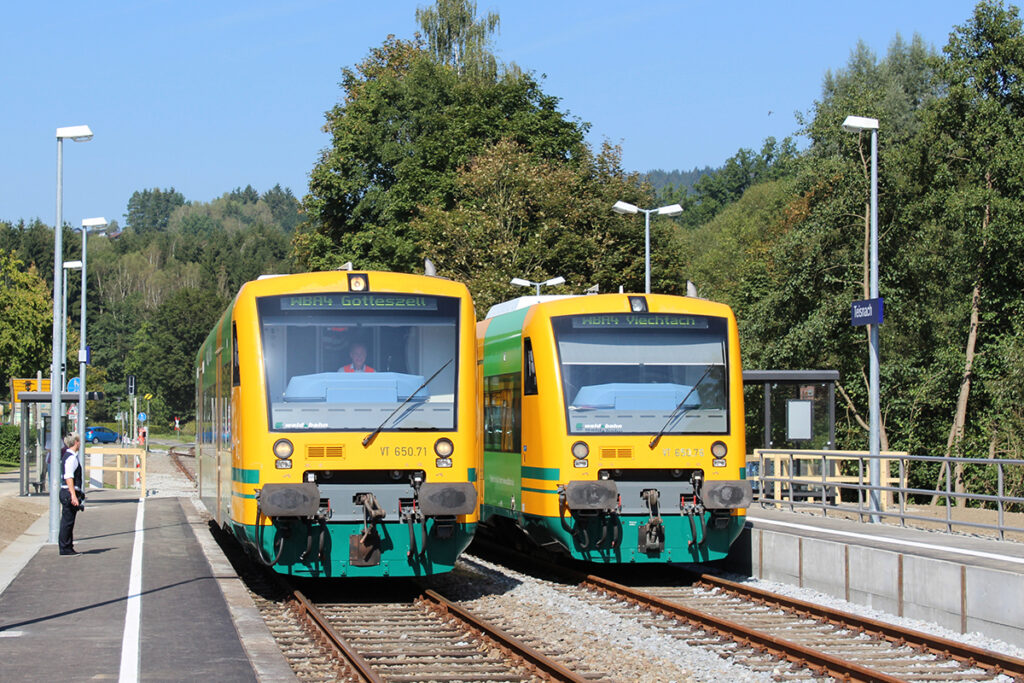 Zwei Triebwagen stehen nebeneinander in einem Bahnhof.