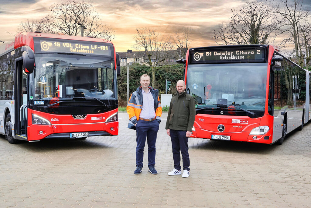 Zwei Personen stehen vor zwei Bussen.