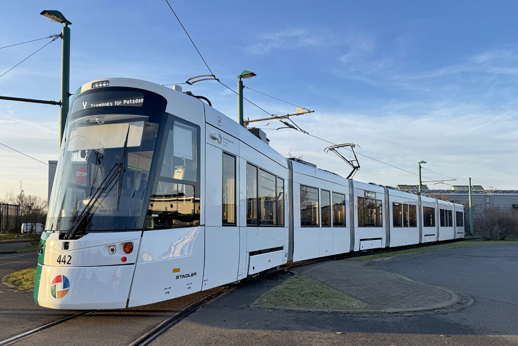 Eine Straßenbahn steht vor einer Halle.