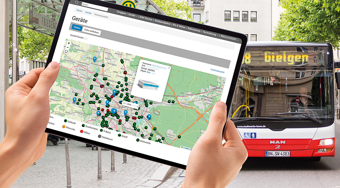 Im Vordergrund halten zwei Hände in Tablet, hinten steht ein Bus.