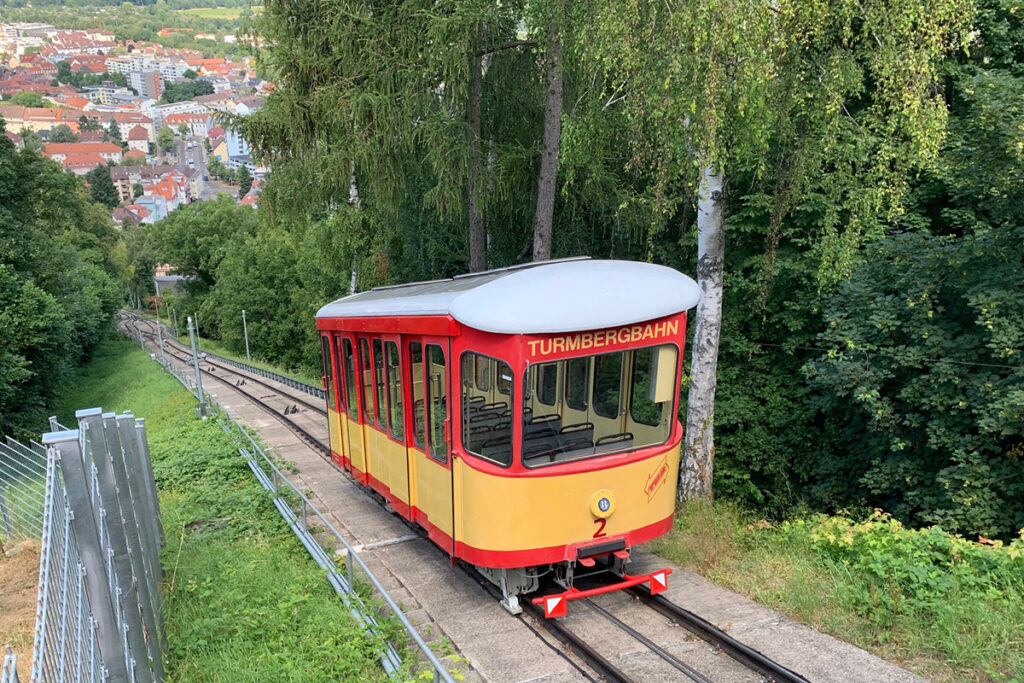 Ein Wagen der alten Turmbergbahn fährt an Bäumen entlang.