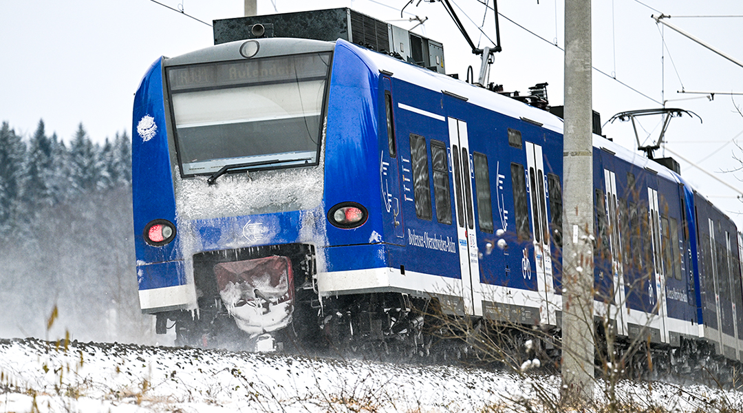 Ein Triebzug fährt durch schneebedeckte Felder.