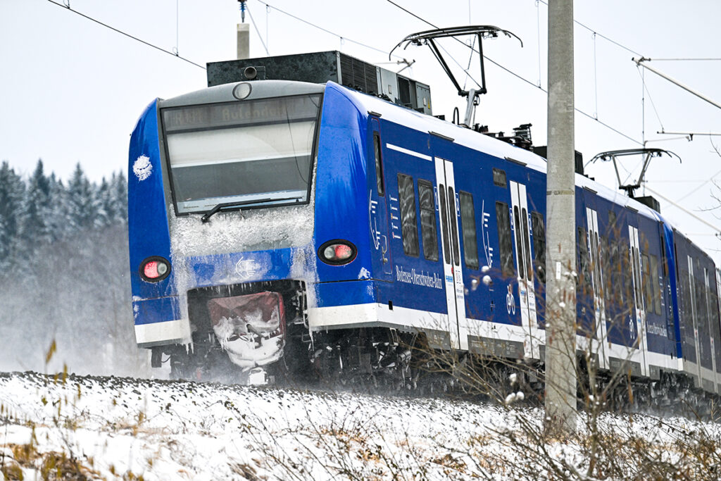 Ein Triebzug fährt durch schneebedeckte Felder.