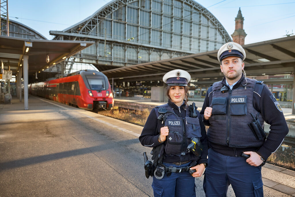 Zwei Polizisten stehen auf einem Bahnsteig vor einem Zug.