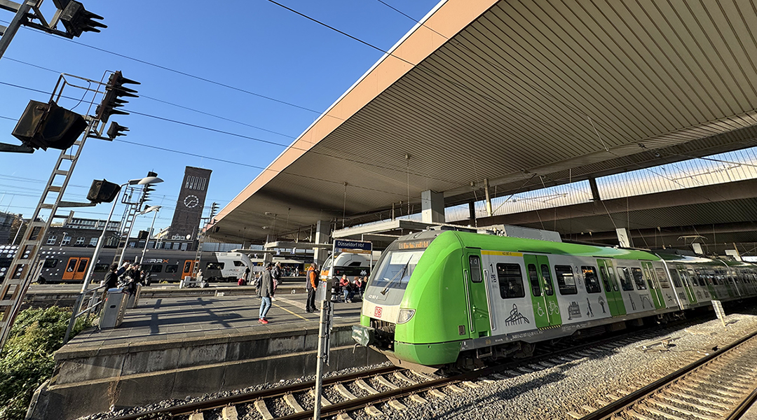 In einen Bahnhof mit vielen Menschen auf en Bahnsteigen fahren Züge ein.