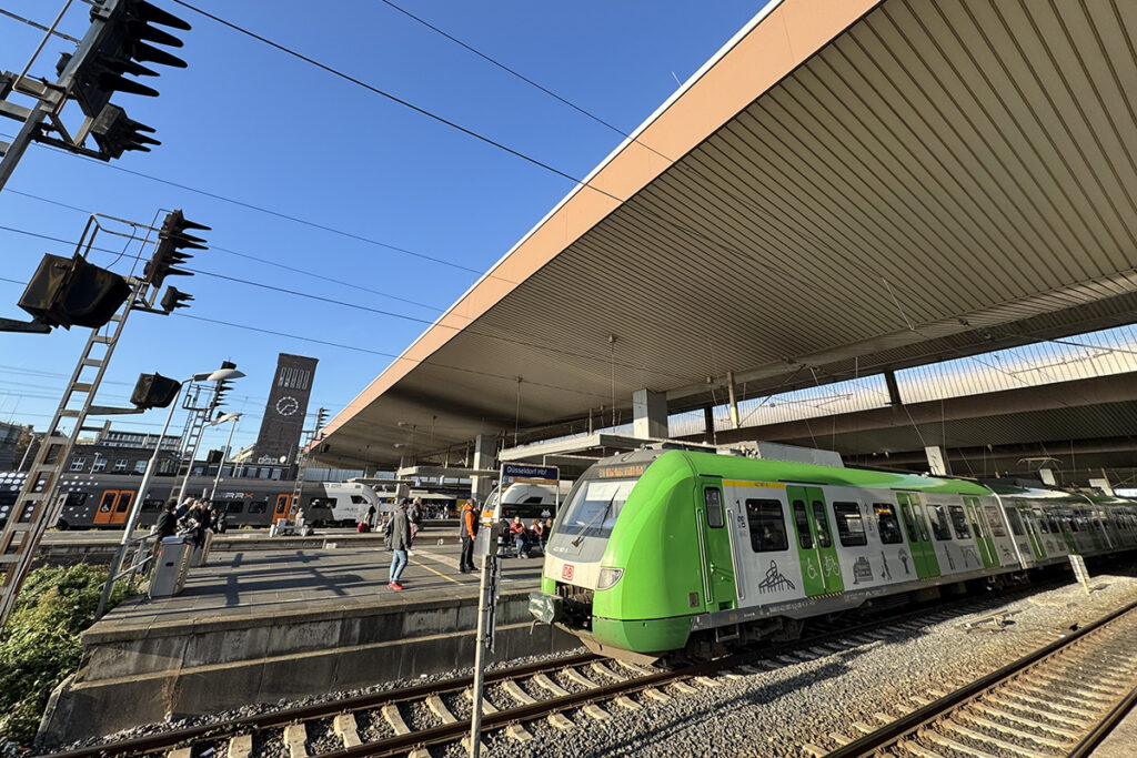 In einen Bahnhof mit vielen Menschen auf en Bahnsteigen fahren Züge ein.