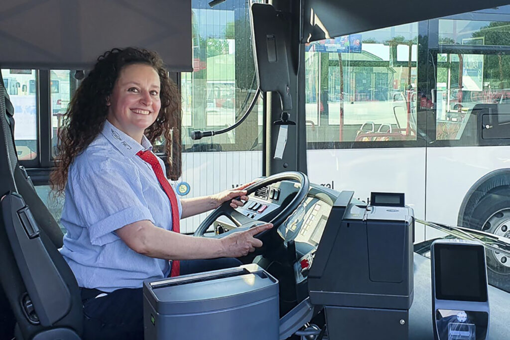 Eine Frau sitzt am Steuer eines Busses.