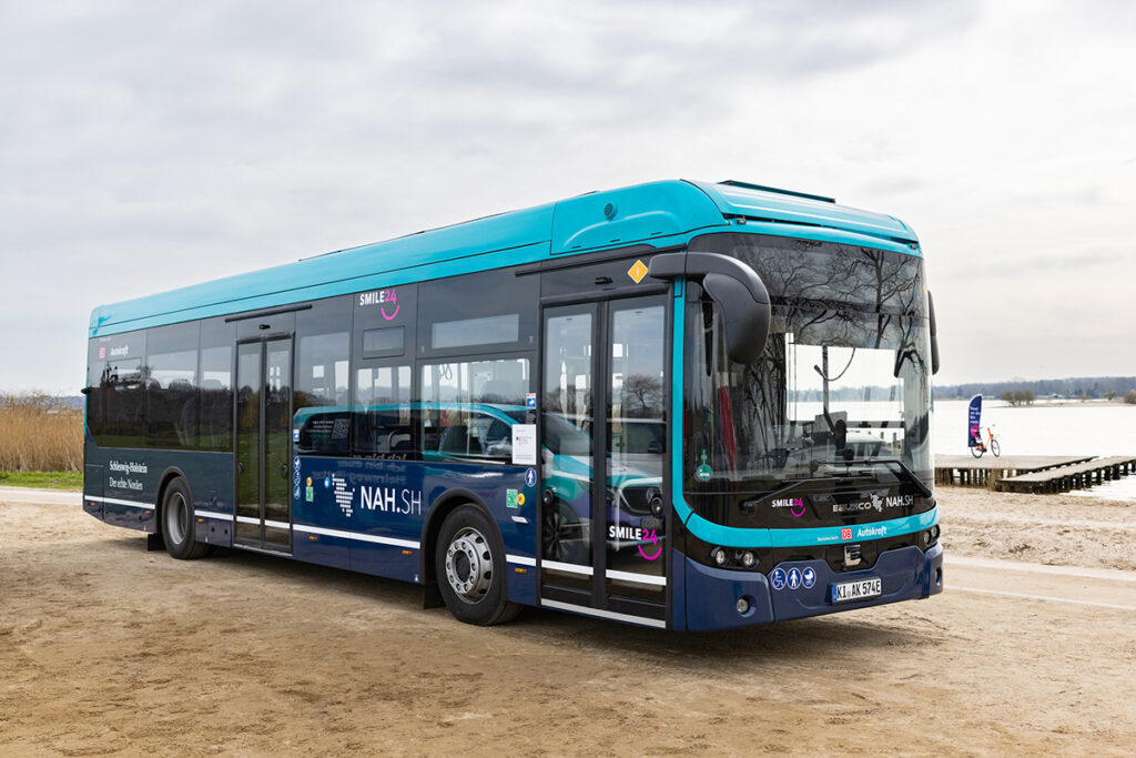 Ein Elektrobus steht vor einem Gewässer.