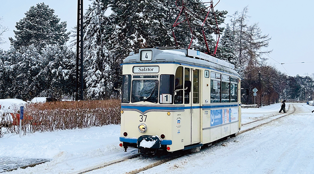Eine Straßenbahn fährt auf einer verschneiten Straße.