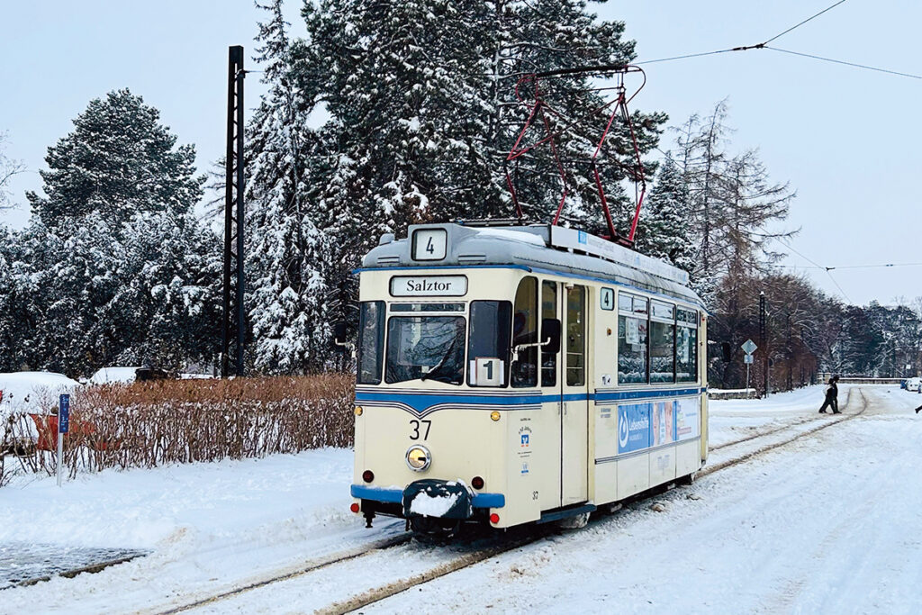 Eine Straßenbahn fährt auf einer verschneiten Straße.