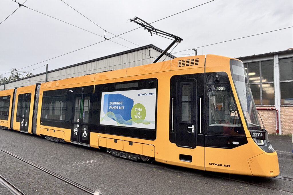 Eine Straßenbahn steht vor einer Halle.