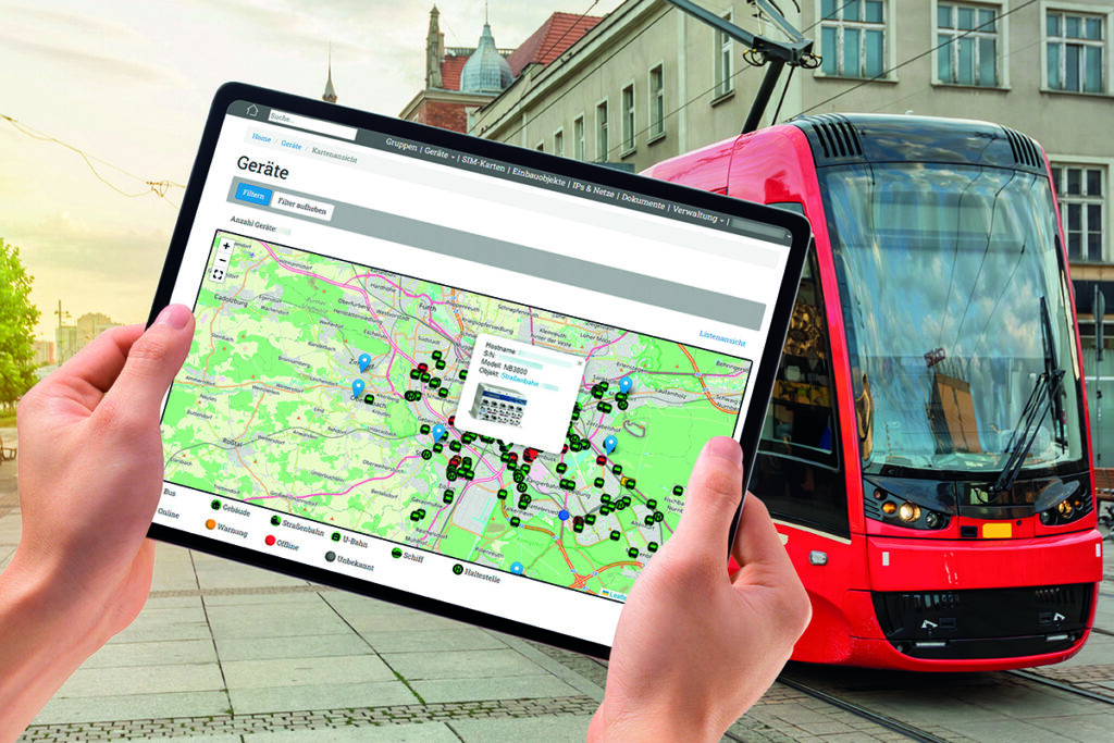Hände halten ein Tablet, dahinter steht eine Straßenbahn.