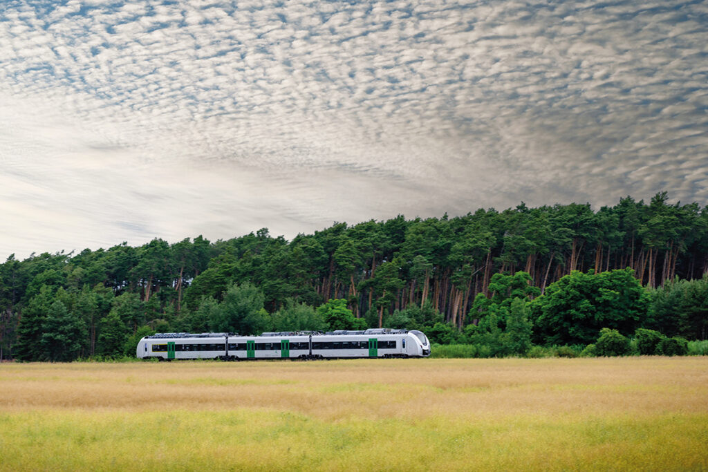 Ein Akkuzug fährt durch Wiesen und Wälder.