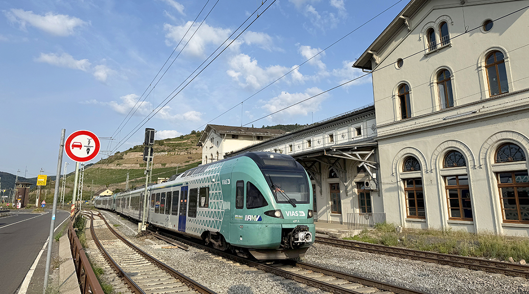 Ein Zug hält vor einem Bahnhofsgebäude.