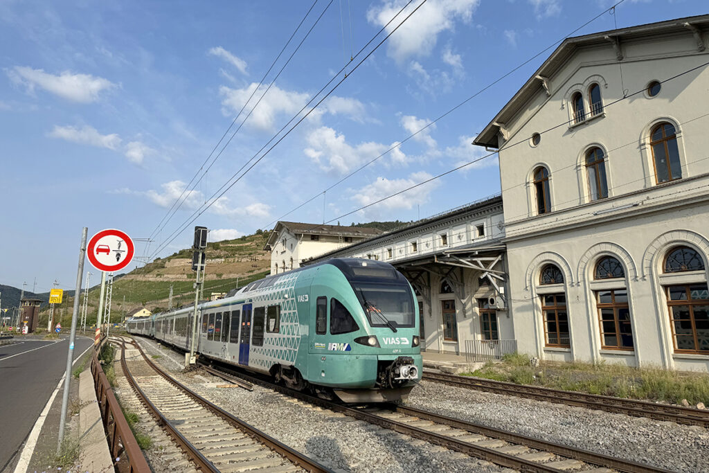 Ein Zug hält vor einem Bahnhofsgebäude.