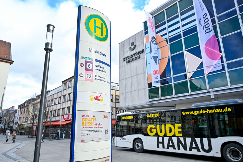 Haltestellenschild einer Bushaltestelle mit einem Bus im Hintergrund.
