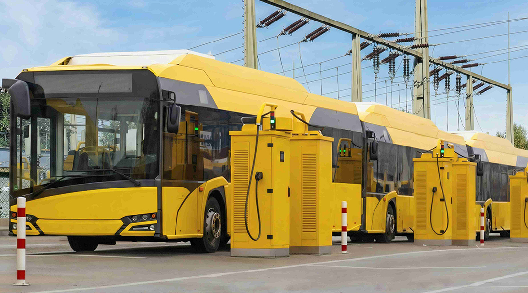 Elektrobusse stehen hintereinander an einer Ladestation.