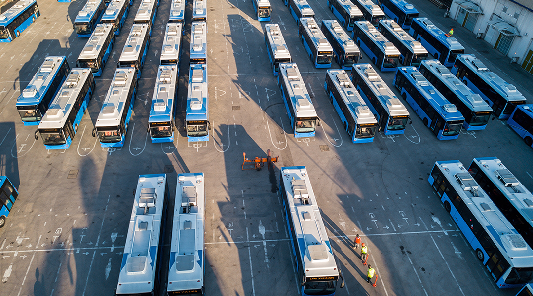 Luftaufnahme von vielen Bussen, die auf einem Platz stehen.