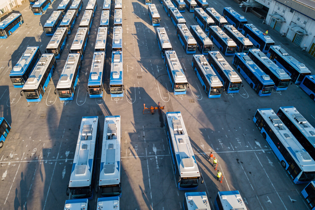 Luftaufnahme von vielen Bussen, die auf einem Platz stehen.