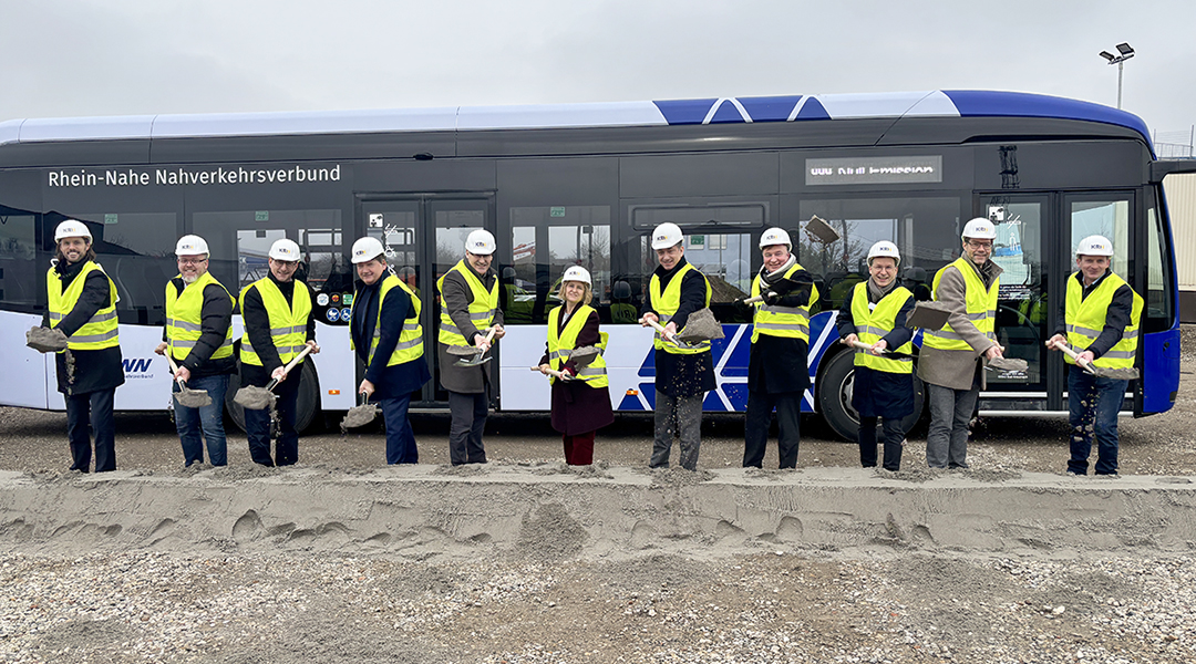 Mehrere Menschen stehen mit Schaufeln in den Händen vor einem Bus.