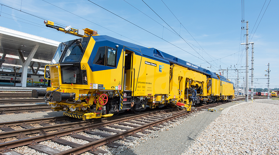 Eine Gleisbaumaschine steht in einem Bahnhof.