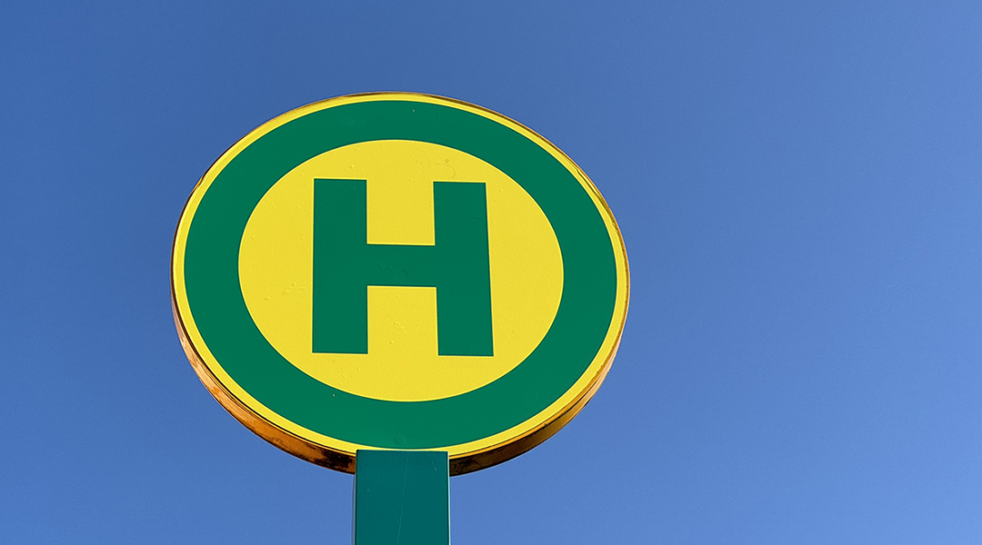 Ein Haltestellenschild vor einem blauen Himmel.