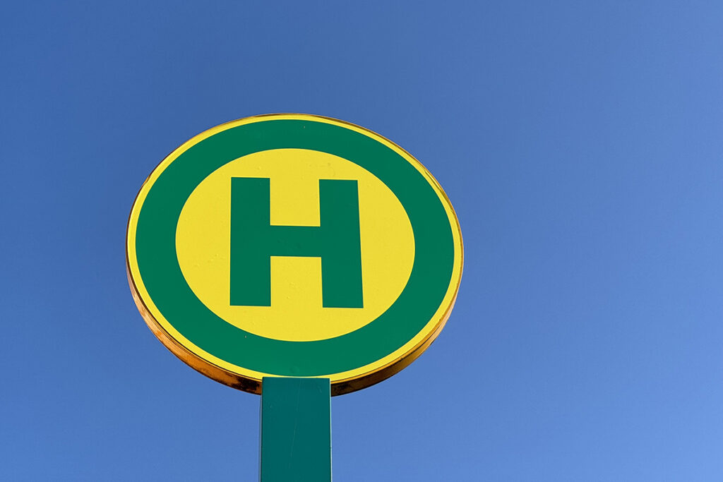 Ein Haltestellenschild vor einem blauen Himmel.