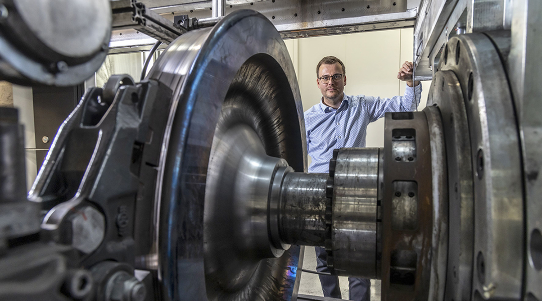 Eine Person steht neben einem Eisenbahnrad.