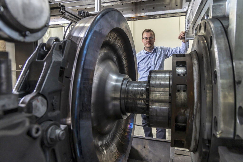Eine Person steht neben einem Eisenbahnrad.