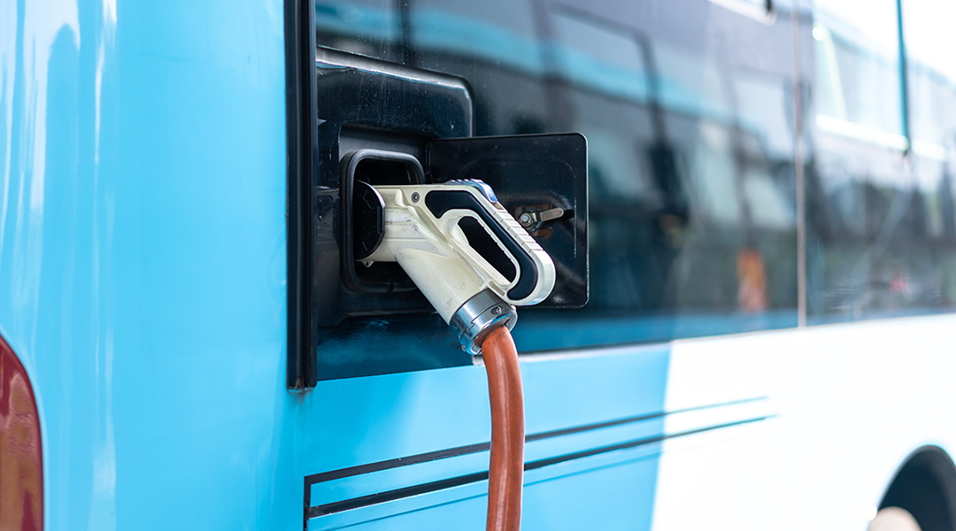 Ein Elektrobus wird mit einem Stecker geladen.