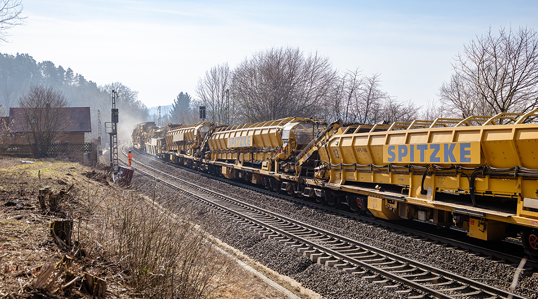 Ein Gleisbauzug steht auf einer zweigleisigen Strecke.