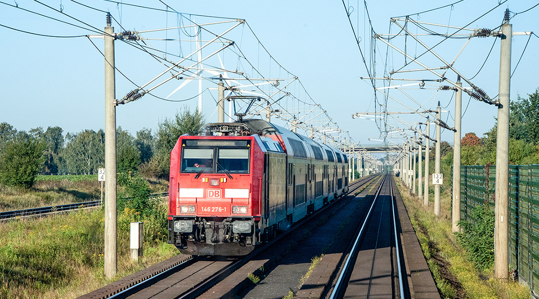 Ein Zug fährt auf einer zweigleisigen Strecke.