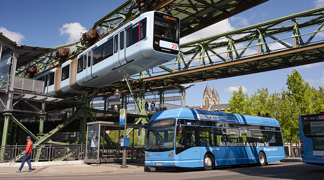 Über einem Stadtbus fährt eine Schwebebahn.