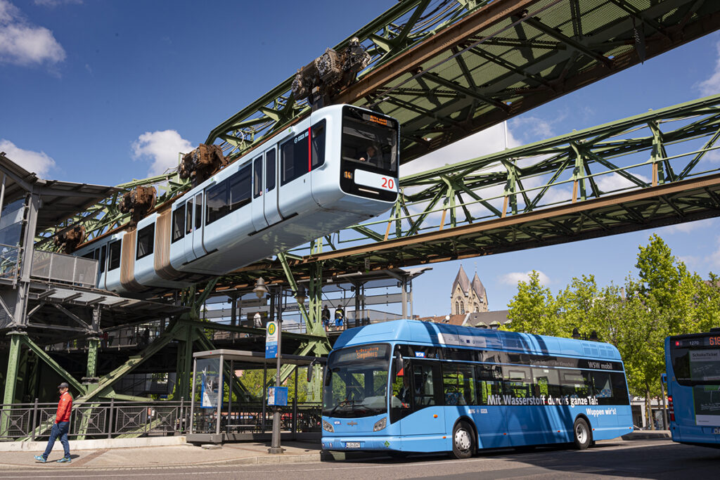 Über einem Stadtbus fährt eine Schwebebahn.