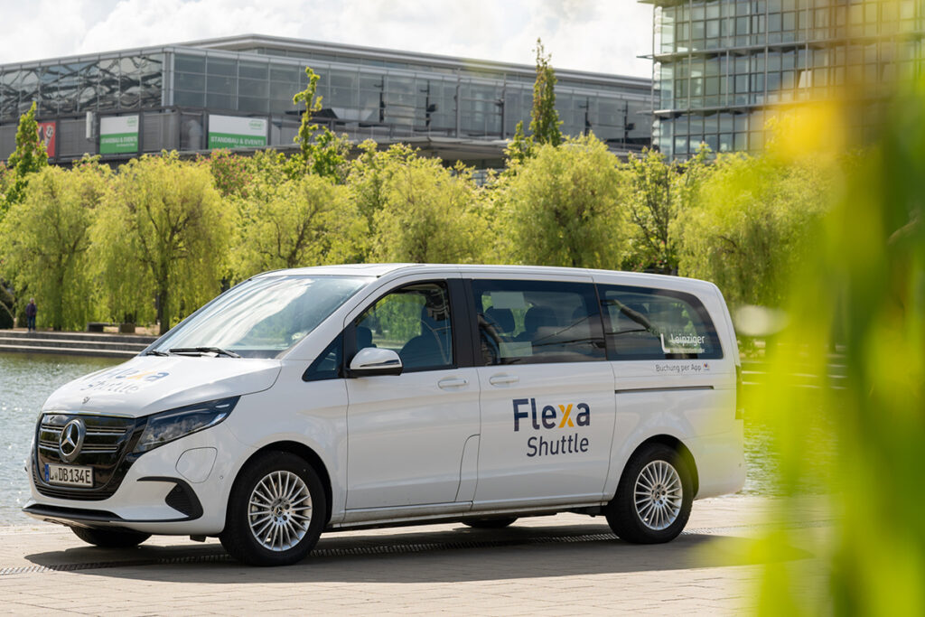 Ein Van steht vor Bäumen und Häusern.