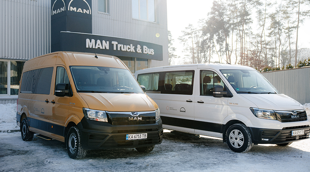 Zwei Kleinbusse stehen vor einem MAN-Firmengebäude.