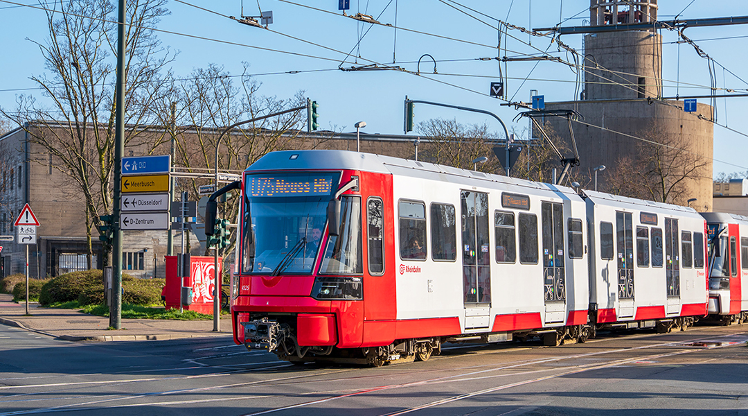 Eine Stadtbahn fährt auf einer Straße.