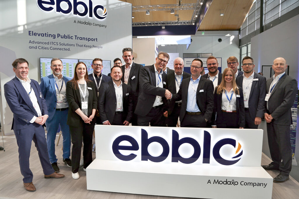 Zahlreiche Personen stehen hinter einem Schild mit der Aufschrift ebblo.