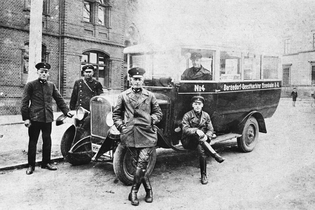 Auf einem historischen Foto stehen Personen vor einem Bus.