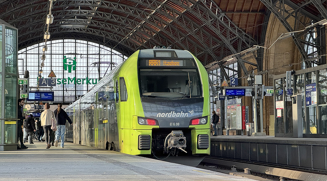 Ein Zug steht an einem Bahnsteig in einer Bahnhofshalle.