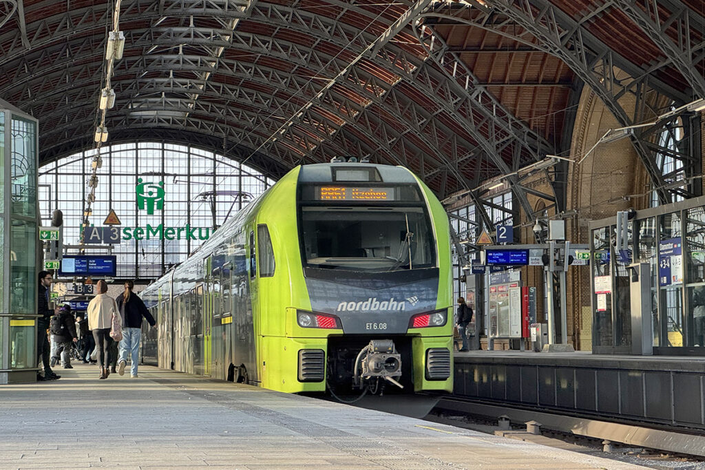 Ein Zug steht an einem Bahnsteig in einer Bahnhofshalle. 