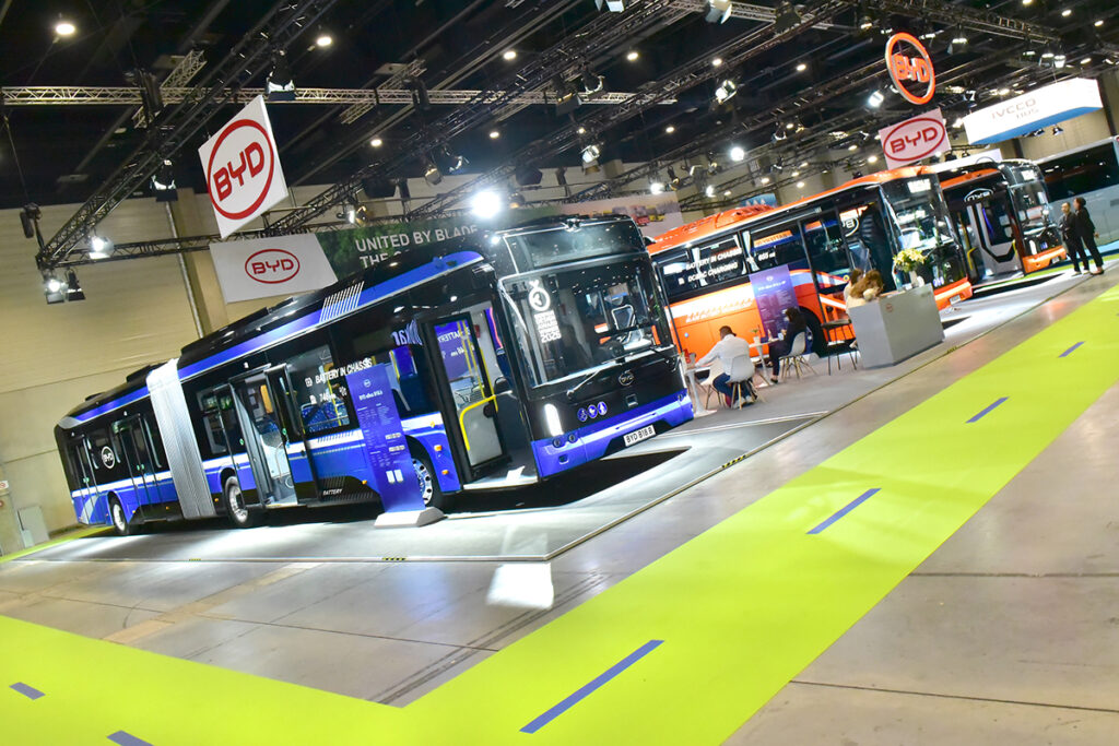 Drei Busse stehen nebeneinander in einer Messehalle.