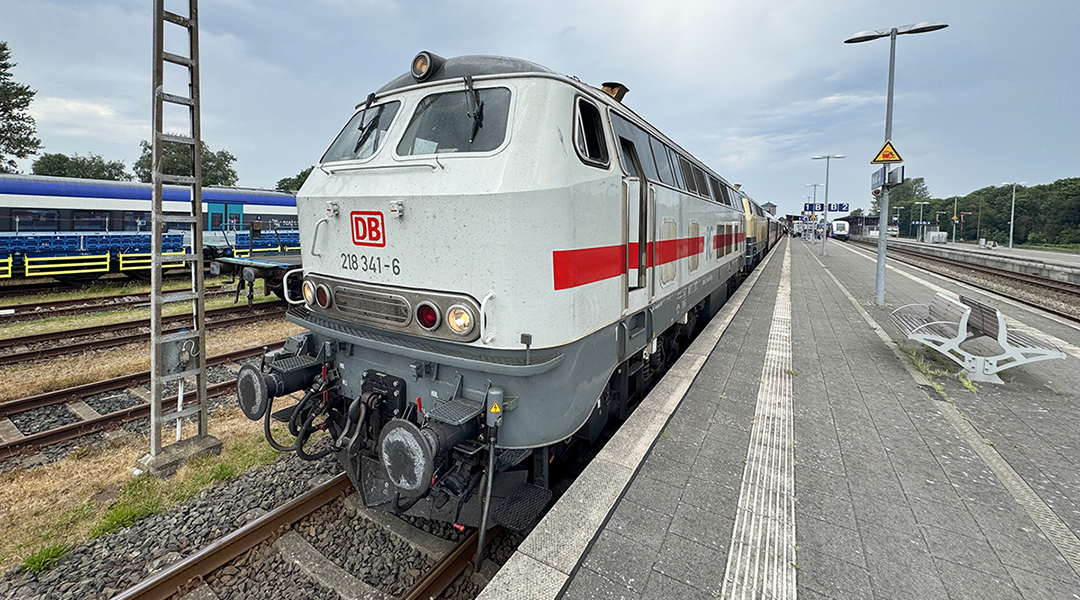 Ein Zug mit zwei Dieselloks steht an einem Bahnsteig.