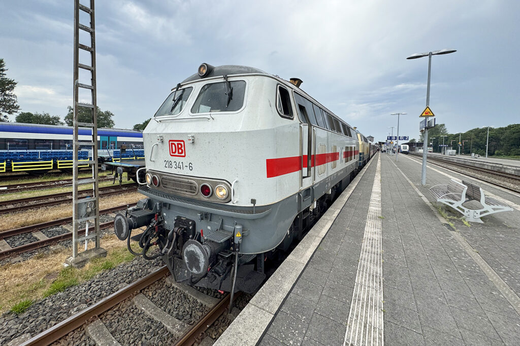 Ein Zug mit zwei Dieselloks steht an einem Bahnsteig.