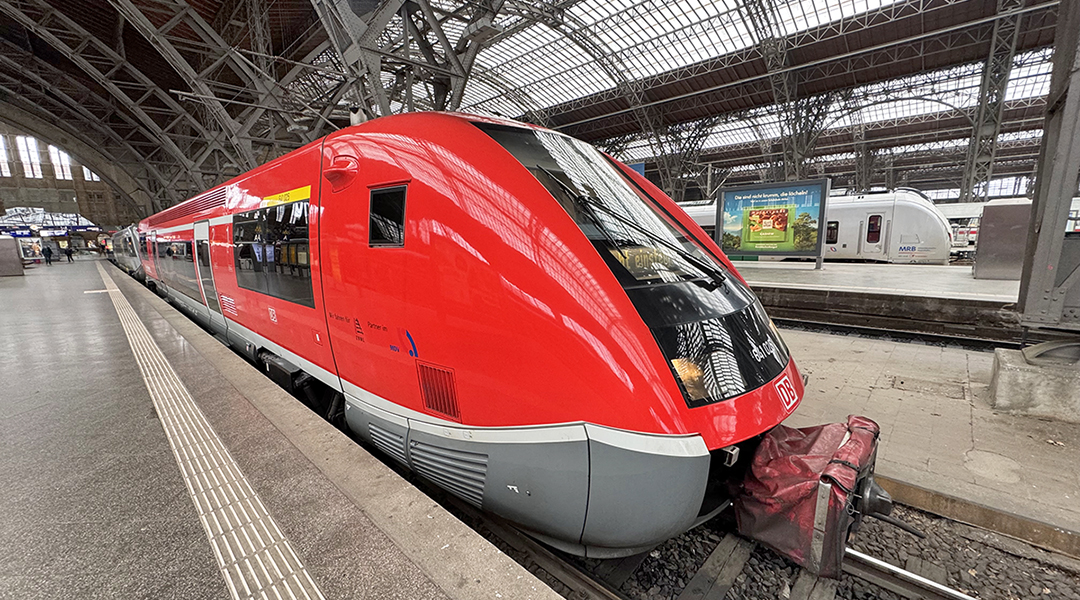 Ein Triebwagen steht in der Bahnhofshalle von Leipzig an einem Bahnsteig.