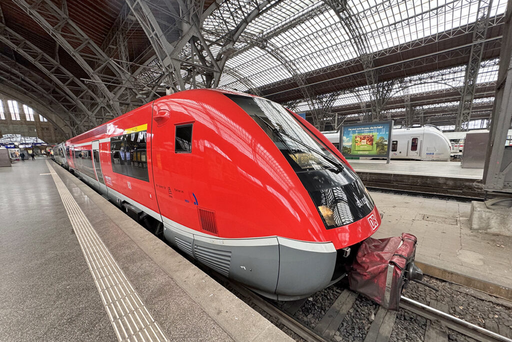 Ein Triebwagen steht in der Bahnhofshalle von Leipzig an einem Bahnsteig.