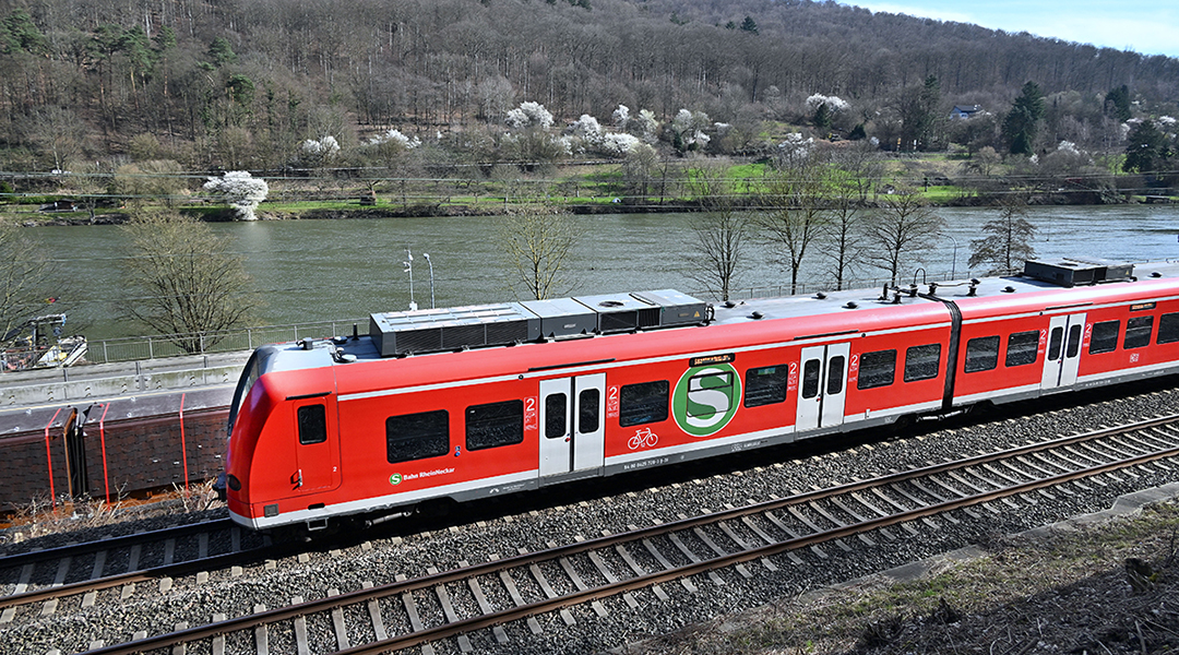 Eine S-Bahn fährt an einem Fluss entlang.